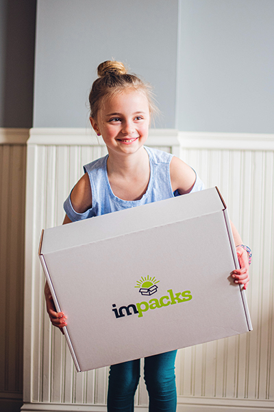 Girl-smiles-while-holding-impacks-box