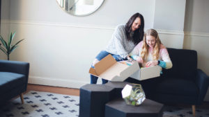 Mother and daughter smile over box of school supplies